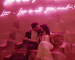 wedding couple sitting in front of pink neon signage