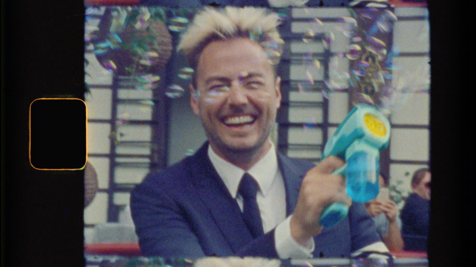 groom smiling while shooting a bubble gun at the camera